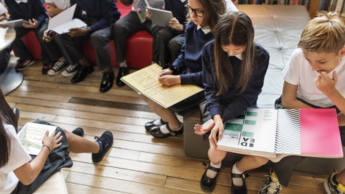 Group of young students looking at books together