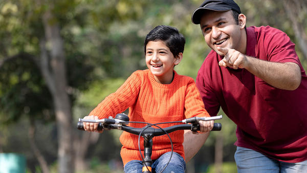 Father si teaching his son to ride a byke in the park