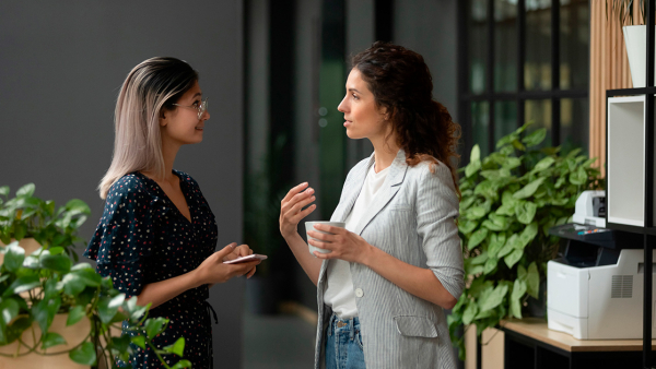 Two women having in conversation in a modern office with plants