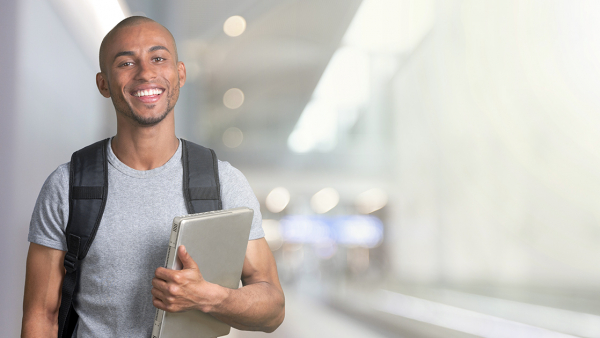 Smiling Black male college student with backpack and laptop