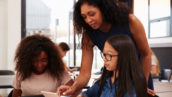 Black female teacher instructs two young students