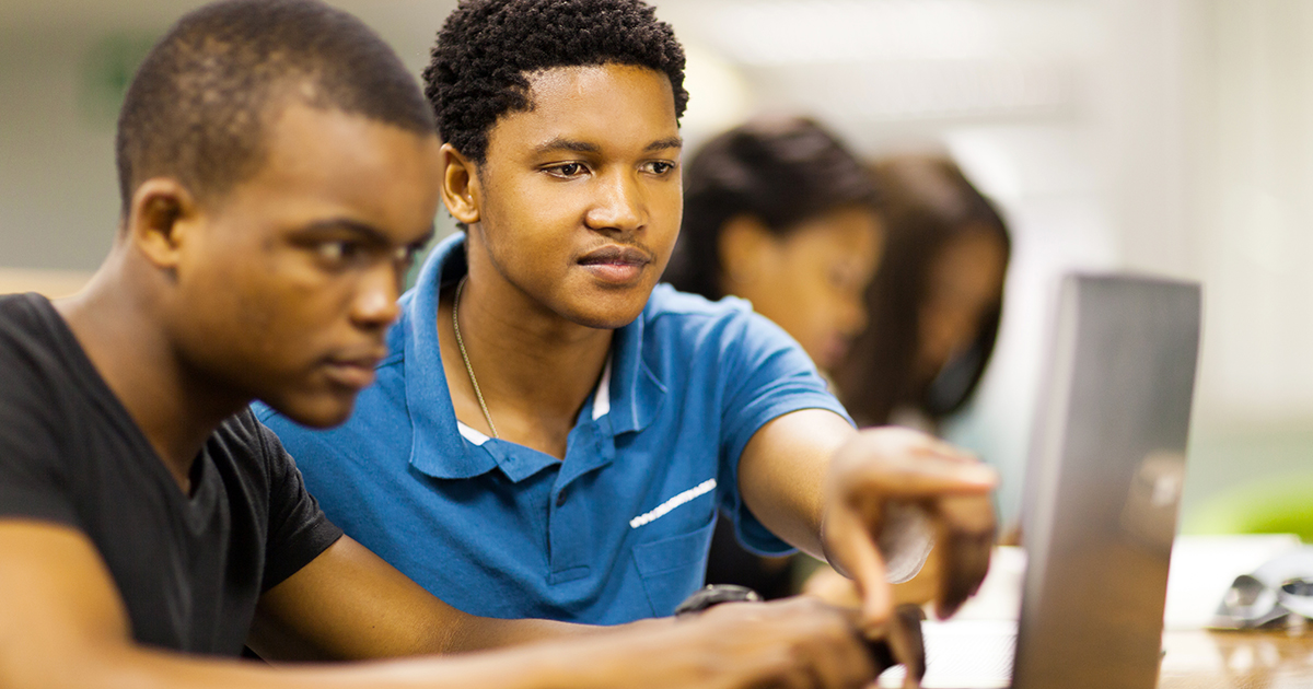Two male students of color look at information on a computer