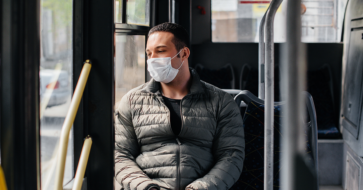 Man wearing face mask riding a bus