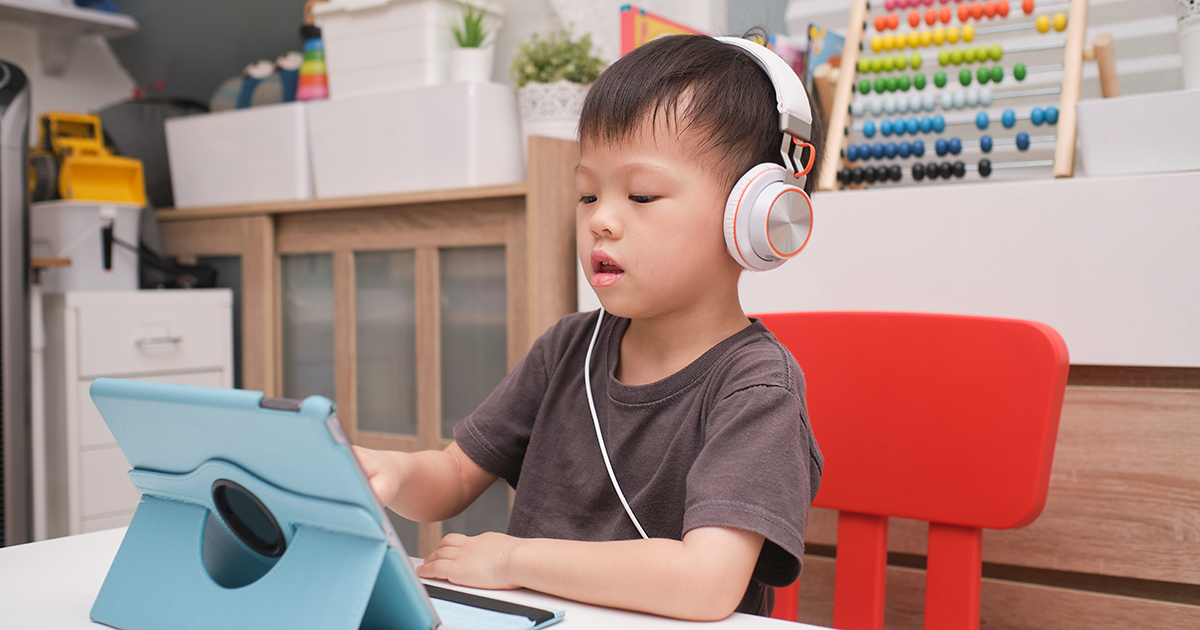 little boy with headphones in front of computer