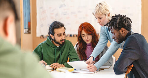 group of young people with a mentor are sitting around of table