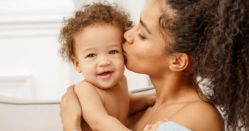 a mother kissing a little baby