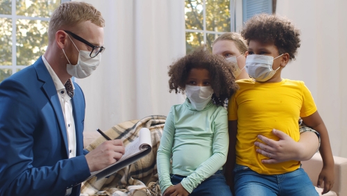 social worker with medical mask visits a family with kids