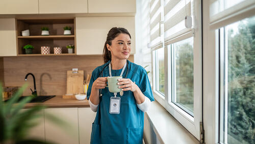a nurse student is standing with a coffee cup