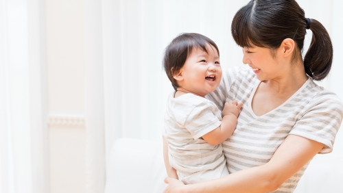 Young Asian mother holding and smiling at her infant