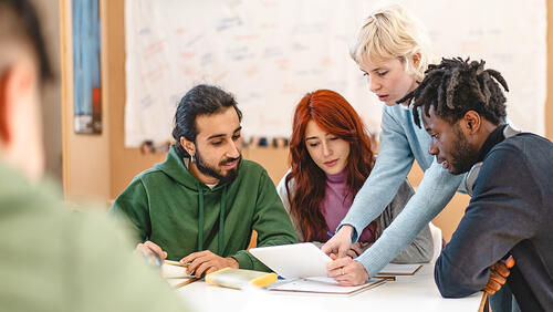 group of young people with a mentor are sitting around of table