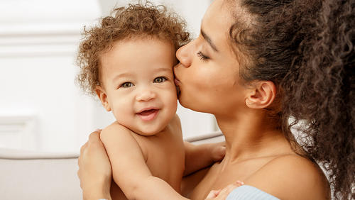 a mother kissing a little baby