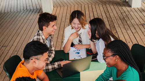 youth people are sitting around the table and discussing a project