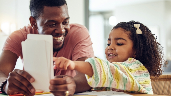 Black man helps young daughter with homework